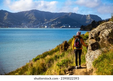 hiker girl admiring the idyllic scenery of lyttelton bay at coastal cliff walk from hays bay to church bay and diamond bay, banks peninsula, canterbury, new zealand - Powered by Shutterstock