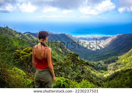 hiker girl enjoys the panorama of oahu island and honolulu in hawaii islands while climbing wiliwilinui ridge trail; hiking on green mountains in hawaii, holidays in hawaii