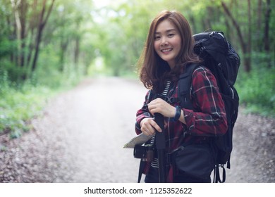 Hiker Girl Outdoor At Nature Forest With Backpack. Happy Asian Woman Hiking Outdoors With Bag , Camera And Holding Map. Hiking Portrait Of Happy Young Female Hiker Smiling Looking At Camera