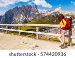 Hiker girl with red backpack taking a rest to admire the view in Parco Naturale Tre Cime, Dolomites Mountains, Italy