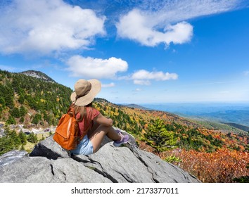 Hiker Girl Sitting On A Cliff Edge Enjoying Scenic Fall View. Woman Relaxing On Top Of Autumn Mountain Grandfather Mountain State Park, Banner Elk, North Carolina, USA.