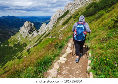 Hiker go along picturesque hiking trail in Tatras (Carpathian Mountains, Poland). Active lifestyle adventure and nordic walking.