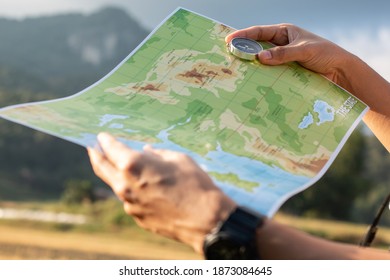 A Hiker Hand Holding A Compass And A Map