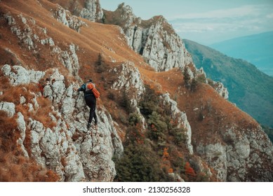 Hiker Hiking On The Top Mountain Cliff. Climber Overcoming A Difficult Climbing Route On The Rock Mountain Cliff. Adrenaline Extreme Sport Outdoor. People Adventure Travel. Sports Challenge.	