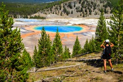 A Hiker Looking Down On Yellowstone National Park's Grand Prismatic Spring In Yellowstone National Park, The Largest Hot Spring In The United States, And The Third Largest In The World. 