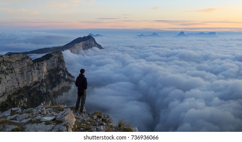 A hiker looking over a sea of clouds in the mountains at dawn. 