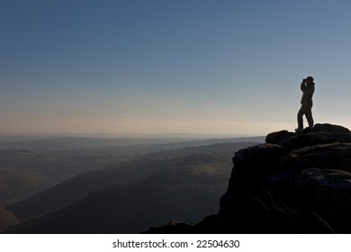 Hiker looks through binoculars over Dartmoor