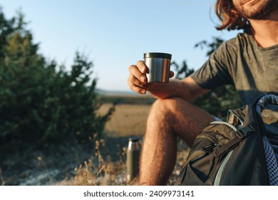 Hiker man with backpack holding thermos in his hand - Powered by Shutterstock