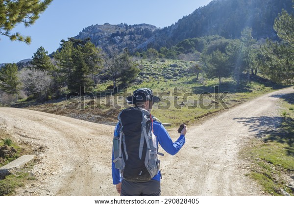Hiker man choose in a road fork\
between two different path directions at the forest in\
mountain