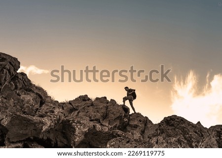 Hiker man climbing up rocky  mountain edge. Going on an adventure. 