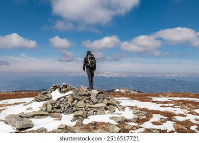 Hiker man standing on rock formation atop of mountain peak Lenzmoarkogel, Gleinalpe, Lavanttal Alps, Styria, Austria. Hiking trail on snow covered alpine meadow. Wanderlust. Tranquil serene scene - Powered by Shutterstock