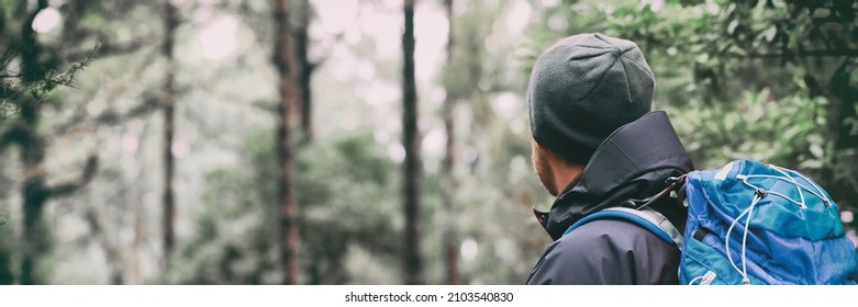 Hiker man walking through woods in winter forest. Hiking outdoor sport active lifestyle. View from the back wearing backpack. - Powered by Shutterstock