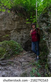 hiker in the narrow gorge in the valley of Brand. narrow passage between field walls and stone blocks, gorge in the Bürser Gorge. Plants illuminated by sunlight glow in the dark. woman in the darkness - Shutterstock ID 2182792163
