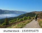 Hiker on the "Great Glen Way" in Scotland, with Scottish highlands and loch in the distance