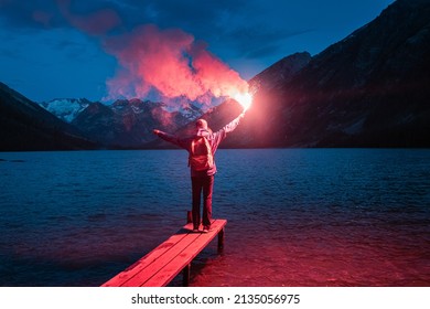 The hiker on the pier lit the emergency red torch and calling for help. Rescue flare and sos signal concept