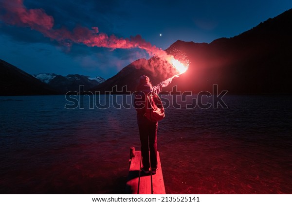The hiker on the pier\
lit the emergency red torch and calling for help. Rescue flare and\
sos signal concept