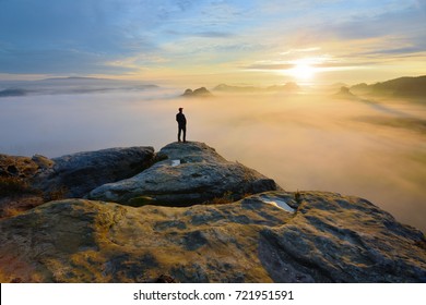 Hiker on rock end above valley. Man watch over misty and autumnal morning valley to bright morning Sun. Tourist  looking to misty valley bellow. Autumn cold weather - Powered by Shutterstock