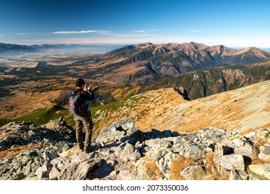 Hiker at peak Krivan in High Tatras mountains making picture of beautiful mountain landscape in Slovakia.