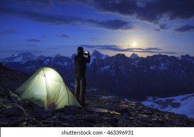 Hiker photographing the moon rising above the famous Matterhorn mountain in Switzerland. Outdoor and adventure concept.