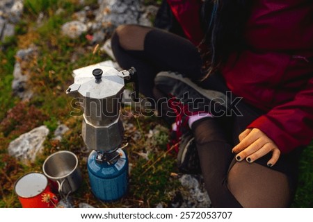 Hiker preparing coffee in the mountains using a traditional italian coffee maker on a portable gas stove