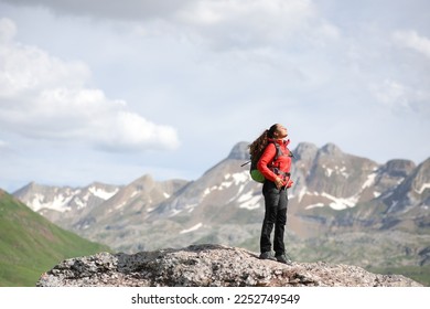 Hiker in red breathing fresh air in the top of a mountain