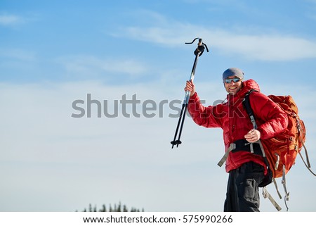 hiker in red down jacket with backpack near the tent in the Carpathians mountains at winter