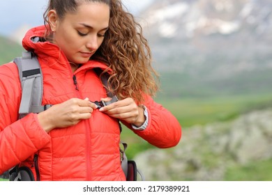Hiker in red fastening backpack strap in the mountain ready to walk