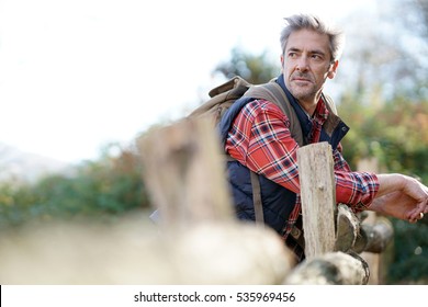 Hiker relaxing by fence on country track