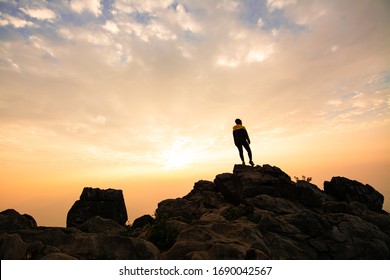 Hiker relaxing on top of a mountain and enjoying valley view during sunrise - Shutterstock ID 1690042567