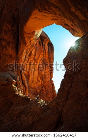 Hiker relaxing under the Double Arch, stone arches of red sandstone formed by erosion, Arches-Nationalpark, near Moab, Utah, United States