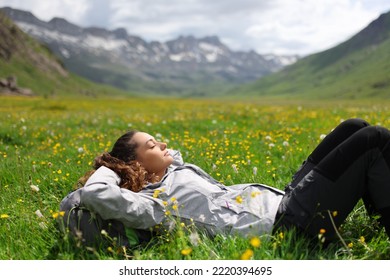 Hiker resting lying on the grass in a valley of a high mountain - Shutterstock ID 2220394695