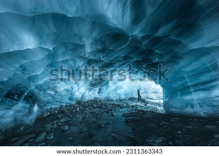 A hiker silhouette exploring an ice cave in the Furgg glacier in Zermatt, Wallis, Switzerland