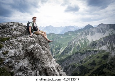 Hiker sits on a mountain cliff of the Allgau Alps - Shutterstock ID 413713549