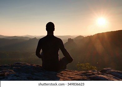 Hiker in squatting position on a rock, enjoy the scenery - Powered by Shutterstock