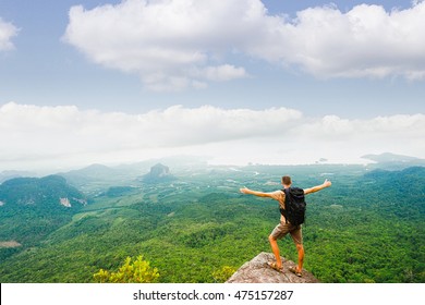 Hiker standing with raised hands and enjoying a beautiful nature from top of mountain. 