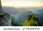 Hiker stands and enjoys valley view from hilly viewpoint. Traveling on hill peaks landscape. Sport, tourism and hiking concept. Watching sunset.