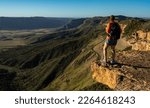 HIker Stands On Rock Shelf Looking Over Mesa Verde National Park