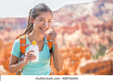 Hiker sunscreen. Woman hiking putting sunblock lotion outdoors during summer hike holidays. Mixed race Caucasian Asian female model.