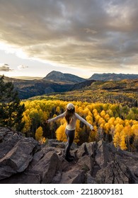 A hiker takes in the fresh air, soaking in the mountain landscape during the peak Autumn Season.  This aspen grove continues for miles towards the mountains and the fall sunset in the distance - Shutterstock ID 2218009181