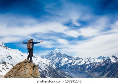 hiker at the top of a rock with his hands raised enjoy sunny day 