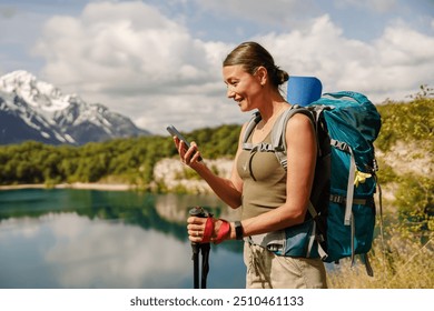 Hiker Using Smartphone while Enjoying the Beautiful Nature at a Scenic Mountain Lake - Powered by Shutterstock