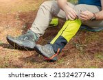 Hiker wears gaiters over trekking boots to protect against water, insects and cold. Clothing and equipment for backpacking and camping