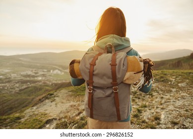 Hiker woman with backpack and sleeping bag walking in the mountains in summer at sunset - Powered by Shutterstock