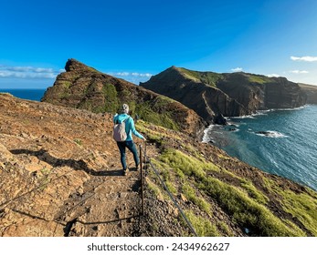 Hiker woman on idyllic hiking trail along rocky rugged cliffs at Ponta de Sao Lourenco peninsula, Canical, Madeira island, Portugal, Europe. Rugged terrain of coastline of Atlantic Ocean. Wanderlust - Powered by Shutterstock