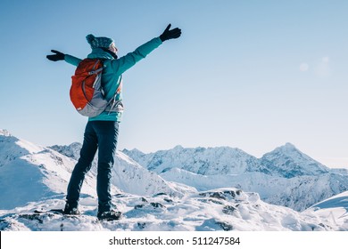 Hiker woman standing with hands up achieving the top, admiring winter mountain landscape. Happy tourist woman in winter. High Tatras, 1987 meter above sea level. Poland, Slovakia