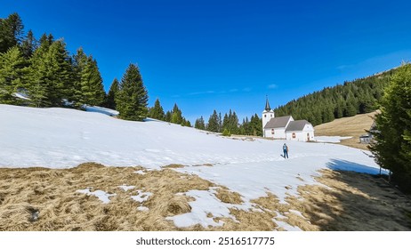 Hiker woman walking to remote church Maria Schnee on Gleinalpe, Lavantal Alps, Styria, Austria. Landmark nestled amidst mountainous landscape, snow-covered hills and dense pine forests. Tranquility - Powered by Shutterstock