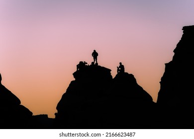 Hikers In Arches National Park, Utah, Watching The Sunrise Near Delicate Arch.