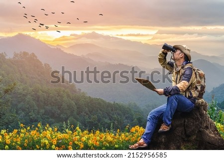 Hikers with backpacks holding binoculars sitting on top of the rock mountain