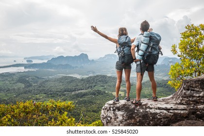 Hikers with backpacks relaxing on top of a mountain and enjoying the view of valley