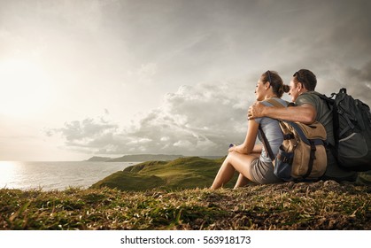 Hikers with backpacks relaxing on top of a hill and enjoying view of sunset in ocean.Island Lombok, Indonesia. Traveling along mountains and coast, freedom and active lifestyle concept